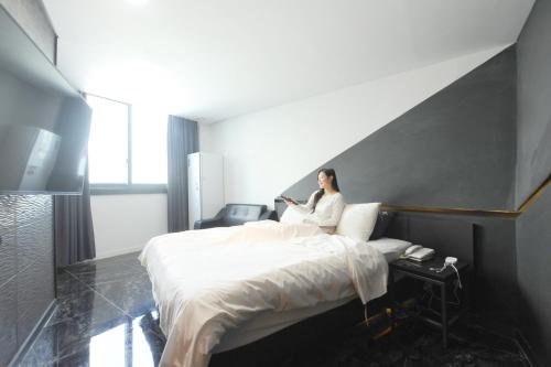 a woman sitting on a bed in a hotel room at K Boutique Hotel in Yeosu