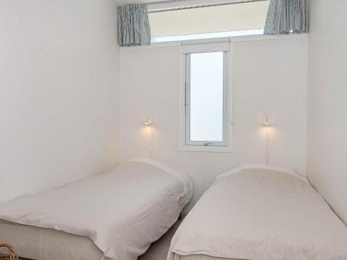 two beds in a white room with a window at Norddjurs Holiday Center in Glesborg