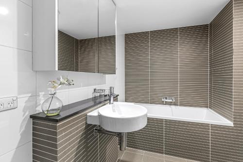 a white bathroom with a sink and a tub at AAN Apartments North Sydney in Sydney