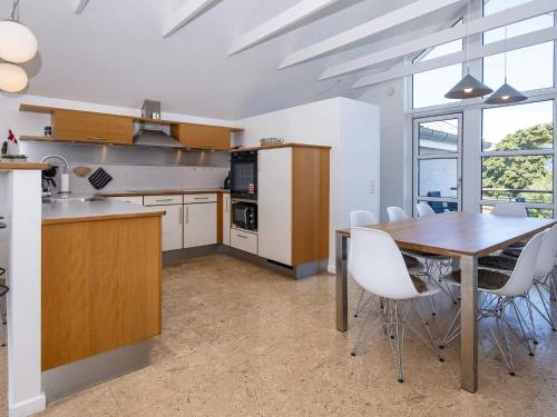 a kitchen with a wooden table and white chairs at Norddjurs Holiday Center in Glesborg