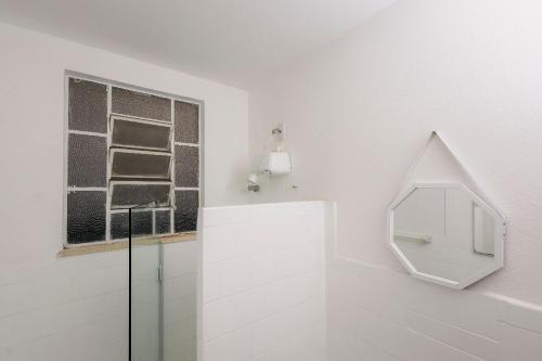 La salle de bains blanche est pourvue d'un miroir et d'une fenêtre. dans l'établissement Apto Comfort Central (Perto de tudo), à São Lourenço