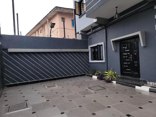 a blue building with a black door and a patio at Caesar's Hotel & Apartment Room #14 in Ikeja