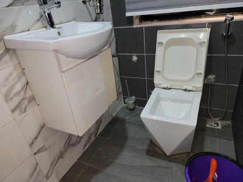 a bathroom with a white toilet and a sink at Caesar's Hotel & Apartment Room #14 in Ikeja
