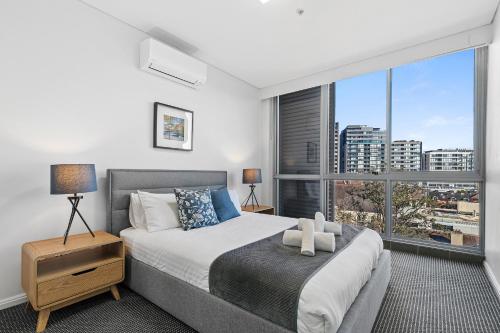 a bedroom with a bed and a large window at AAN Apartments North Sydney in Sydney