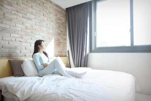 a woman sitting on a bed in a bedroom at K Boutique Hotel in Yeosu