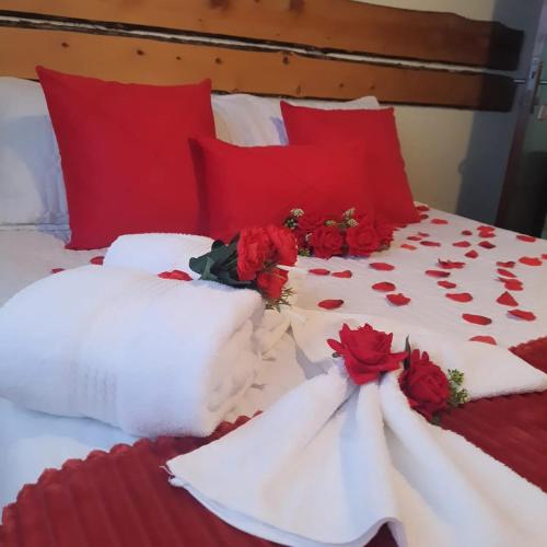 a bed with red pillows and red roses on it at Pousada Valle do Sol in Campos do Jordão
