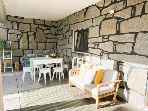 a living room with a stone wall and a table and chairs at Cortecasa, between the sea and nature in Cortegaça