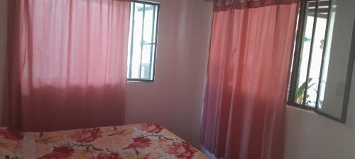 a bedroom with red curtains and a bed and a window at Finca Las Hamacas- La Posada del pensamiento in Santa Beatríz