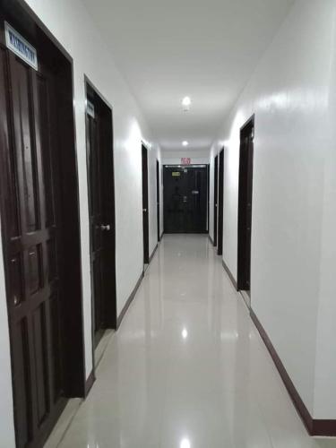 a hallway of a building with black doors and white floors at Lei Kendee in Digos