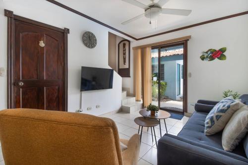 a living room with a blue couch and a tv at Coco - Laguna Azul Poolside Condo in Coco