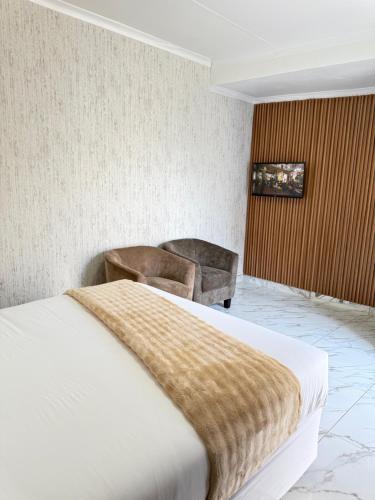 a hotel room with a bed and a chair at Malrose guesthouse Windhoek in Windhoek