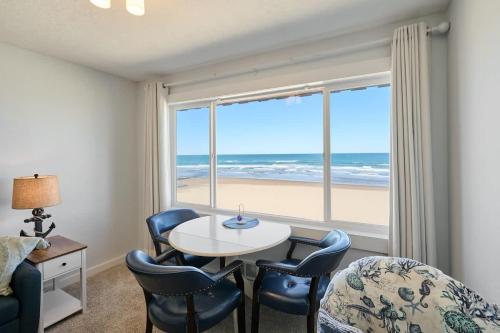 a living room with a table and chairs and a view of the beach at Oceanfront Suite - Top Floor - Pool and Sauna - Sleeps 6 in Lincoln City