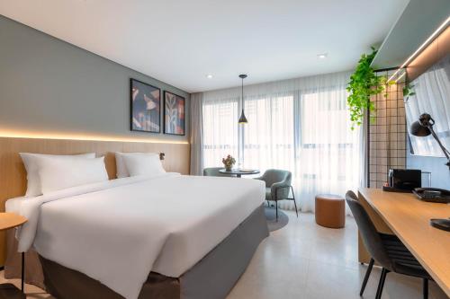 a bedroom with a large white bed and a desk at Cozzy Premium Paulista Hotel in Sao Paulo