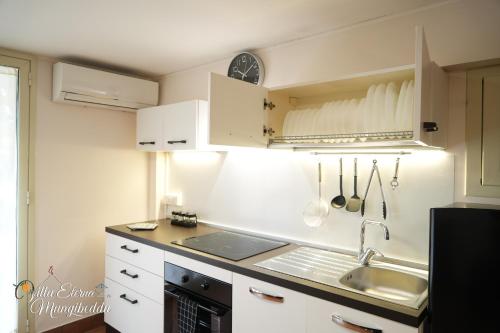 una cucina con mobili bianchi e un lavandino di Villa Eterna Mungibeddu a Paterno