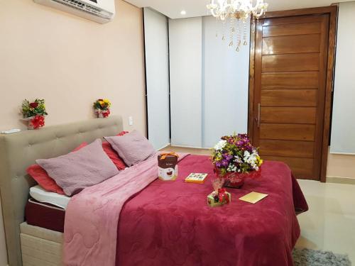 a bedroom with a bed with a pink blanket and flowers at Linda casa confortável em Manaus in Manaus