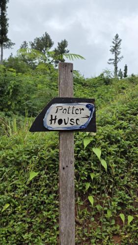 a sign on a wooden post in front of a bush at Potter House TSUKAMOTO Vue sur Baie de Maroe in HUH