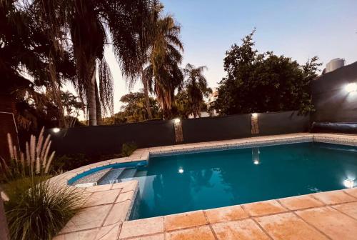a swimming pool in a backyard with a fence and palm trees at Casa Don Tori Paso de la Patria in Paso de la Patria