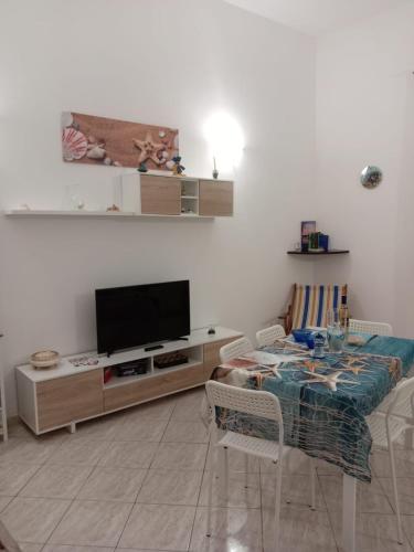 a living room with a flat screen tv and a table at Sweet Home Rosa in Marsala