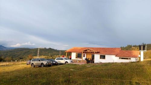 a house with cars parked in front of it at Refugio del Sauce Cabaña 1 Tibasosa- Boyacá in Tibasosa