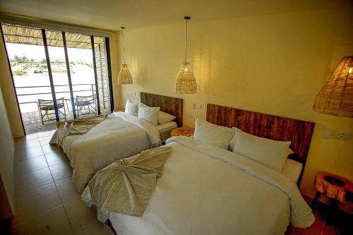 a hotel room with two beds and a window at La Pausa Hotelbistro in Guatapé