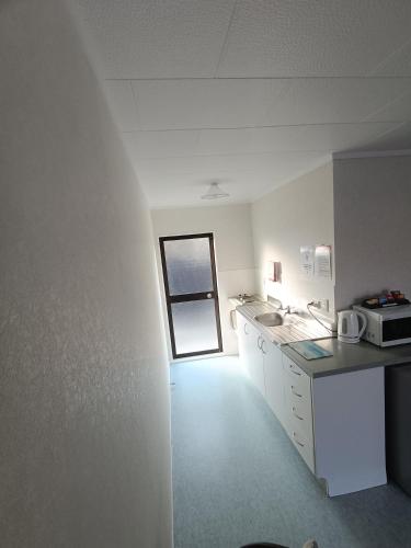 a room with a kitchen with a sink and a window at Opononi Lighthouse Motel in Opononi
