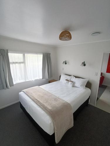 a bedroom with a large white bed and a window at Opononi Lighthouse Motel in Opononi