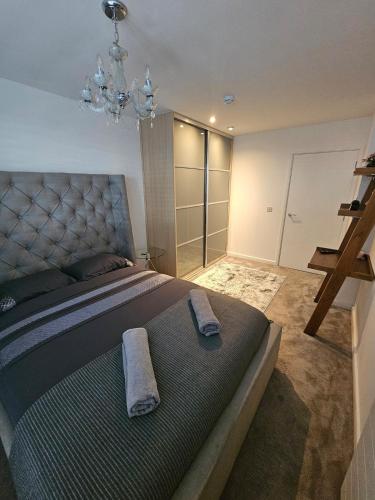 a bedroom with a large bed and a chandelier at Executive E15 Apartment - Skyline Terrace & Free Private Parking - 5-min Walk to Abba Arena in London