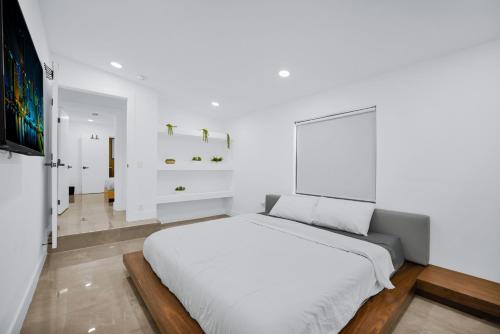 une chambre blanche avec un lit et une télévision dans l'établissement Lux Modern 4BR Villa with Pool in Miami, à Miami