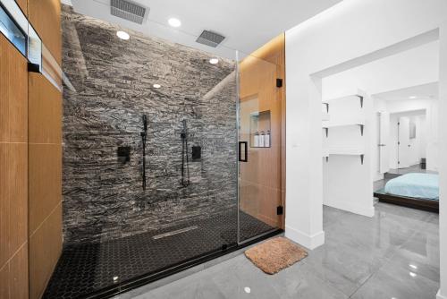 La salle de bains est pourvue d'une douche et d'un mur en pierre. dans l'établissement Lux Modern 4BR Villa with Pool in Miami, à Miami