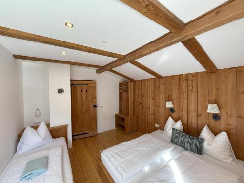two beds in a room with wooden walls and beams at Carmaliva in Innerkrems