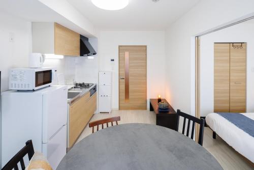 a kitchen and dining room with a table and a bed at Hotel Hs Park Chitose in Chitose