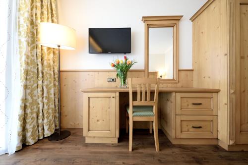 a room with a desk with a mirror and a lamp at Aparthotel Garni Monte in Kartitsch