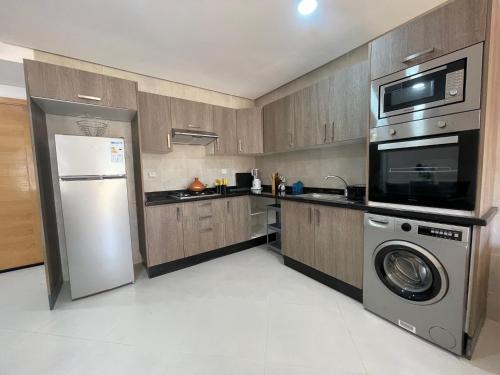a kitchen with a refrigerator and a washer and dryer at Cosy apartment in Bouznika in Bouznika