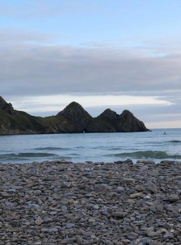 a rocky beach with mountains in the water at Heyboys in Swansea