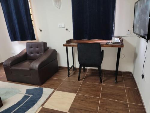 a room with a desk and a chair and a table at Caesar's Hotel & Apartment Room #6 in Ikeja