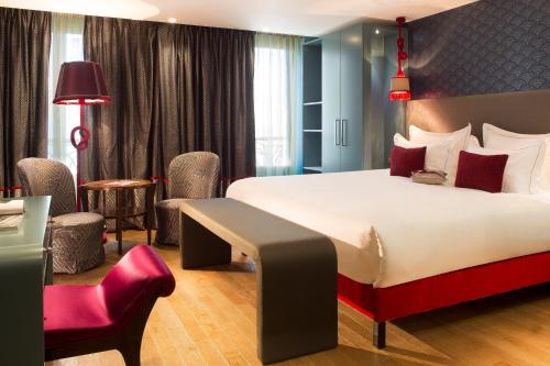 パリにあるムッシュ カデ ホテル ＆ スパの大きなベッドと赤い椅子が備わるホテルルームです。