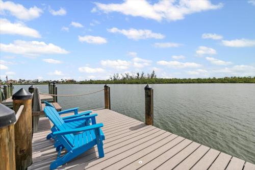 two blue chairs sitting on a dock near the water at Private Bayfront Beach House with Dock, Steps to Beach and Restaurants in Englewood