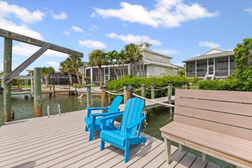 two blue chairs sitting on a dock next to a bench at Private Bayfront Beach House with Dock, Steps to Beach and Restaurants in Englewood