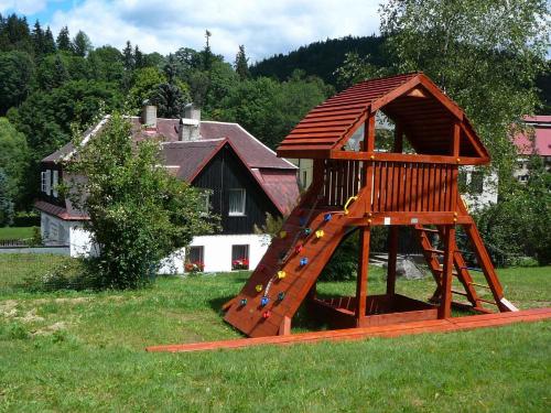 a wooden playground with a slide in the grass at Holiday home in Josefuv Dul 1726 in Josefuv dul
