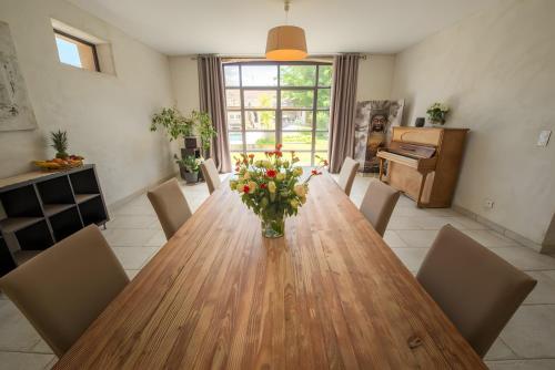 a dining room with a wooden table with a vase of flowers at Le Mas Du Batadou in Visan