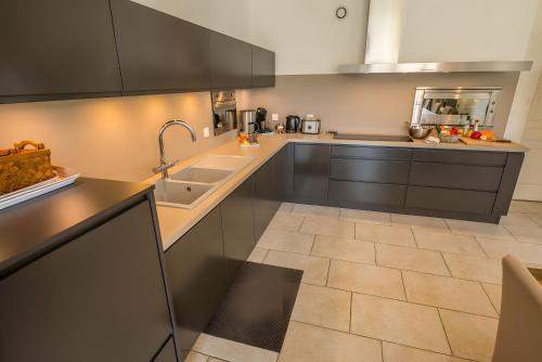 a kitchen with black cabinets and a tile floor at Le Mas Du Batadou in Visan