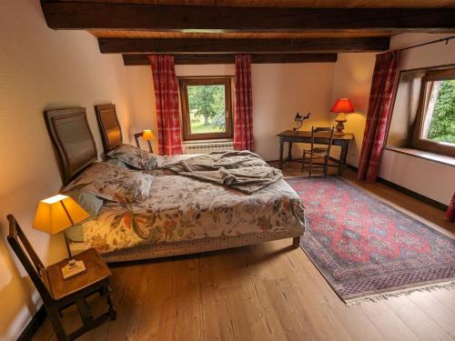 una camera con un letto e un tavolo e due finestre di Superbe Ferme Rénovée avec Cheminée, Wifi, et Jeux Extérieurs près de Gérardmer et Épinal - FR-1-589-28 a Belmont-sur-Buttant