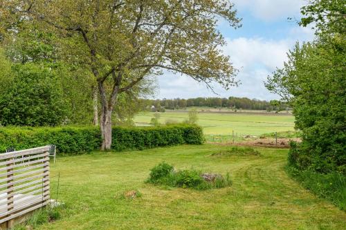 a park bench in a field with a tree at Swedish Cottage By Forest And Lake In Småland in Traryd