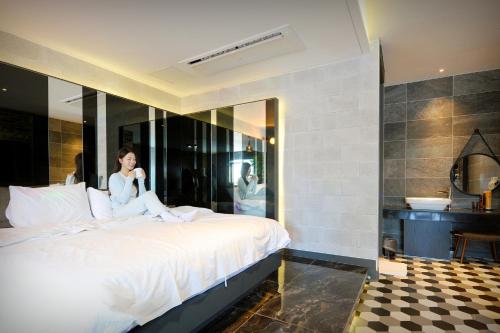 a woman sitting on a bed in a hotel room at K Boutique Hotel in Yeosu