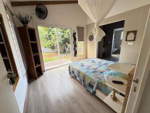 a bedroom with a bed and a table and a window at Villa du FORT in Goyave
