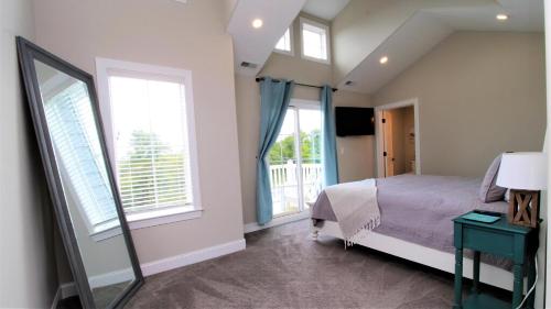 1 dormitorio con 1 cama, 2 ventanas y espejo en Coastal Sanctuary, en West Cape May