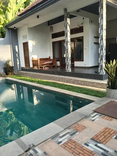 a villa with a swimming pool in front of a house at Rumi Villa in Ubud