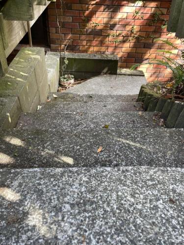 a sidewalk next to a brick building with stairs at tranquil cosy bush cabin in Lower Hutt