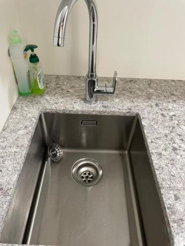 a stainless steel kitchen sink with a faucet at tranquil cosy bush cabin in Lower Hutt