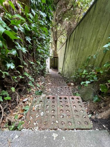 a brick path with a gate and a wall at tranquil cosy bush cabin in Lower Hutt